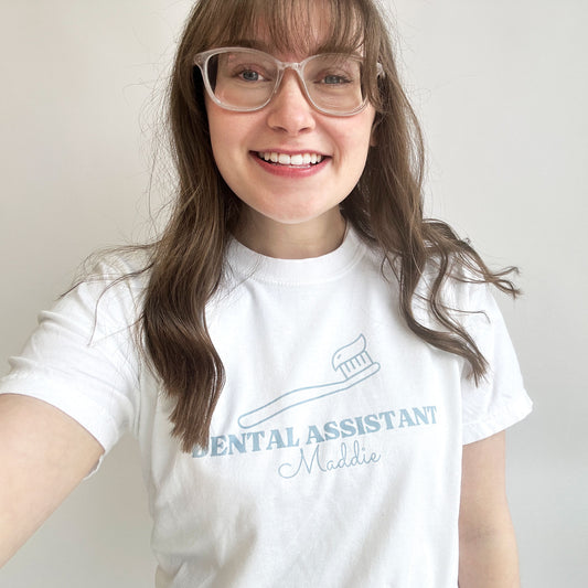 young woman wearing a white comfort colors tee with a dental assistant printed design on the front