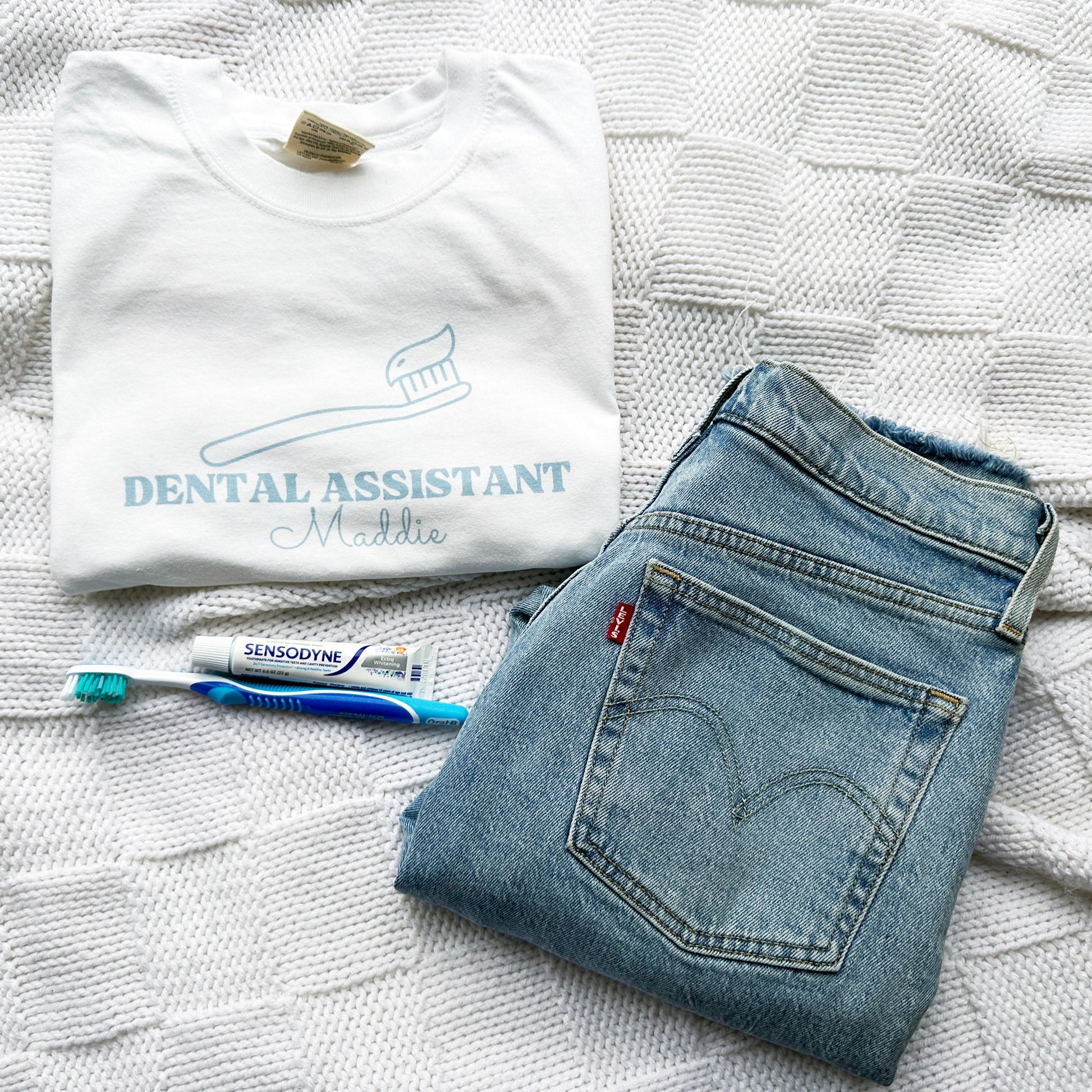 white dental assistant tee with jeans and a toothbrush