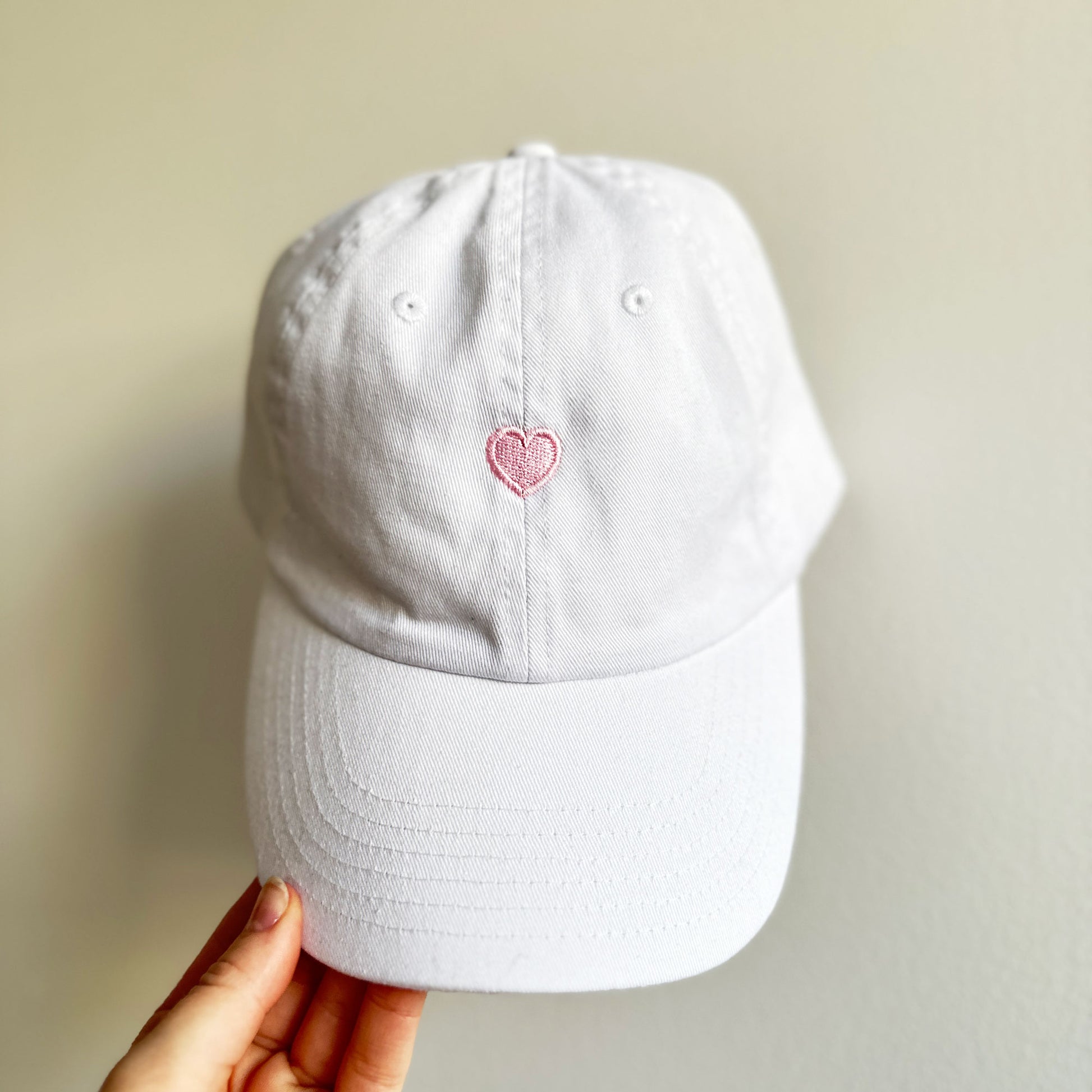 white baseball cap with small baby pink embroidered heart design