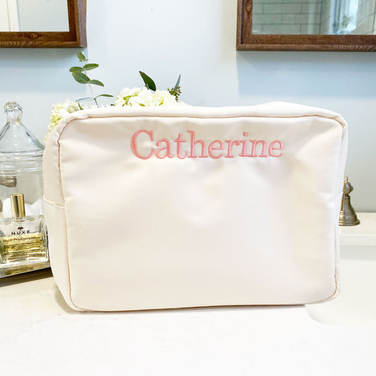 ivory large nylon makeup bag featuring a personalized name embroidery along the top enter of the bag