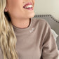 close up of a tan crewneck sweatshirt with the name kayla embroidered in white on the neckline