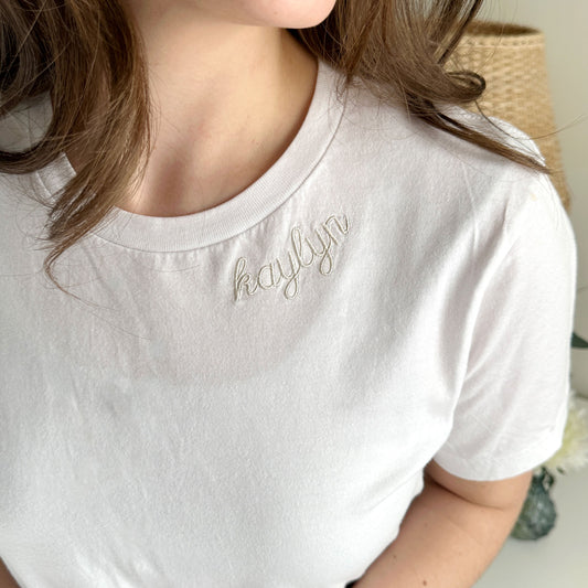 white bella and canvas crewneck tee with kaylyn embroidered in natural thread along the neckline