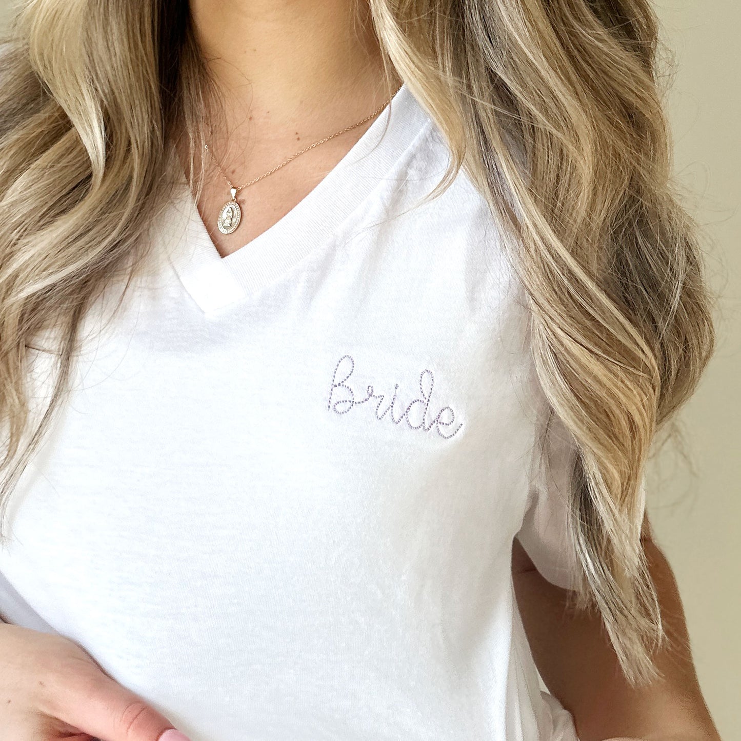 white vneck tee with bride embroidered in a stitch script small on the left chest in lilac thread