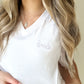 white vneck tee with bride embroidered in a stitch script small on the left chest in lilac thread