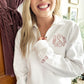 young woman wearing a bridal white quarter zip sweatshirt with monogram on the left chest and wedding date on the sleeve embroidered in mauve pink thread