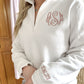 close up of monogram and cuff date embroidered on a white quarter zip sweatshirt