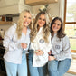 three ladies wearing button down tops with three letter monogram embroidery on the pockets