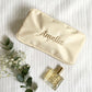nylon cream cosmetic pouch with Amelia embroidered in script and camel thread across the center