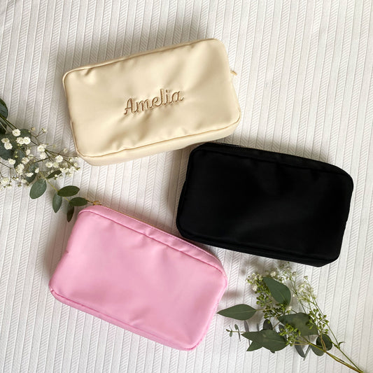 flat lay of cream, pink, and black nylon cosmetic pouches