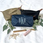 styled nylon makeup pouches in taupe, navy and black. the navy features an embroidered monogram in baby blue thread