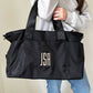 woman holding a black nylon weekender duffle with a custom three letter monogram