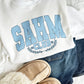white sweatshirt with a custom SAHM Club print with personalized date, jeans, and slippers