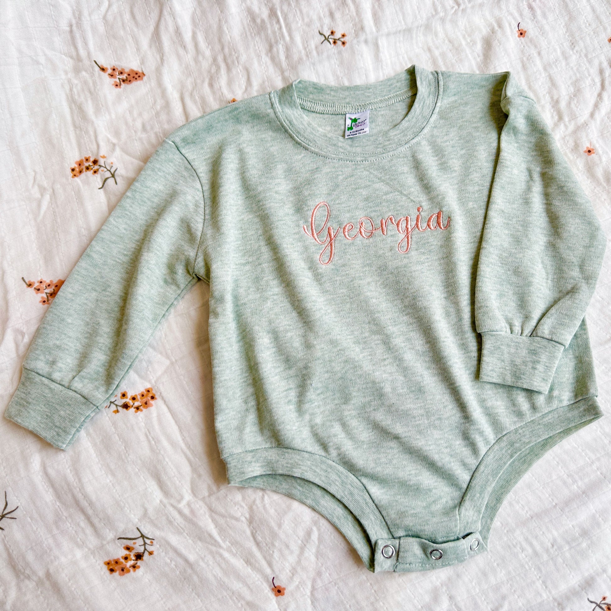 lightweight baby romper in a sage green with georgia embroidered across the center chest in a peach colored thread
