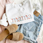 styled flat lay of spring floral embroidered mama on a white crewneck sweatshirt