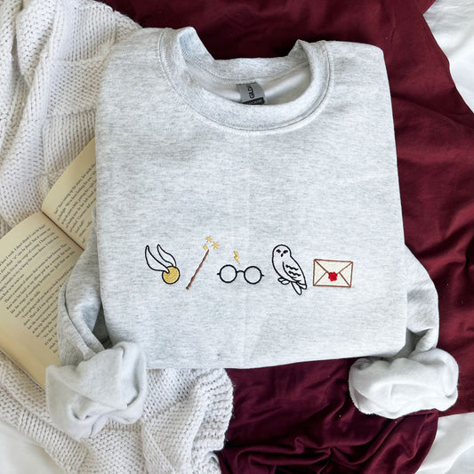 custom harry potter embroidered sweatshirt featuring a golden snitch, wand, glasses, owl, and envelop icons