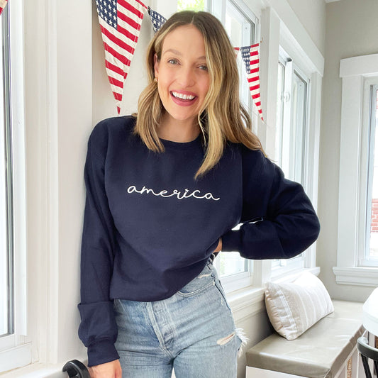 woman wearing a navy blue embroidered crewneck sweatshirt