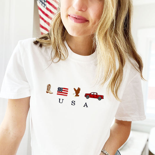 woman wearing a white comfort colors t-shirt with cute embroidered usa icons and usa design