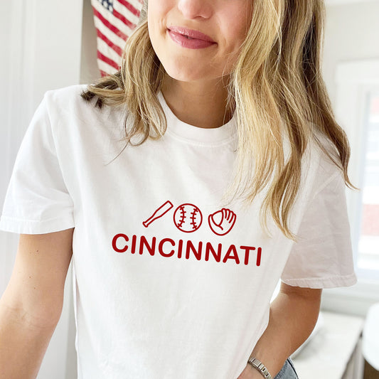 young woman wearing a white comfort colors tshirt with prunted Cincinnati design and baseball icons in red ink