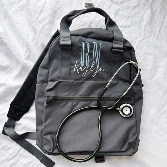 charcoal grey backpack with handles embroidered with nursing credentials and name