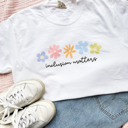 a white t-shirt with a multi-color floral inclusion matters printed design on the front