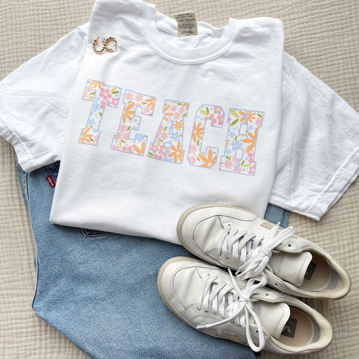 outfit for teacher featuring a white comfort colors t-shirt with cute large TEACH floral printed design across the chest.