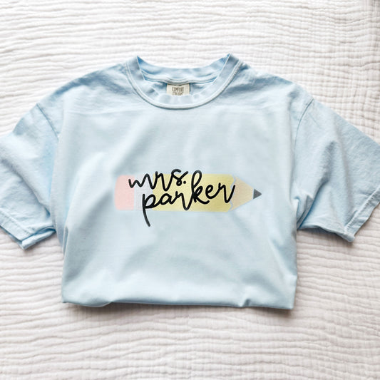 custom comfort colors t-shirt with a large printed pencil design with custom name in a script font