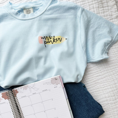 cute chambray blue comfort colors t-shirt with mini pencil and name printed design on the left chest