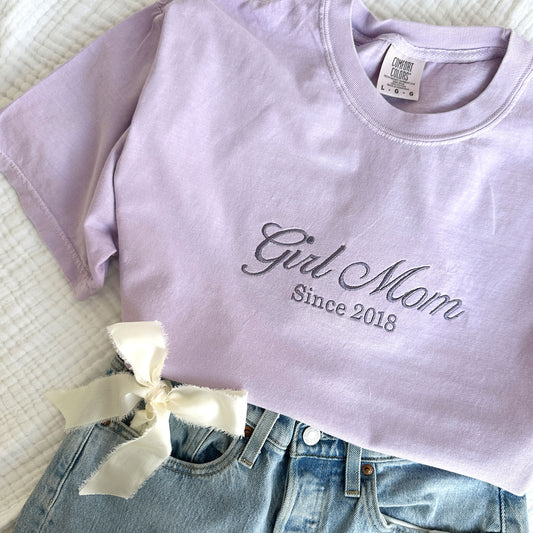 Orchid comfort colors t-shirt with embroidered Girl Mom since custom date design across the chest in smoky orchid thread. Styled with jeans and a bow