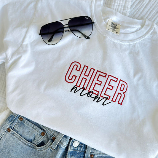 styled flat lay of a white comfort colors t-shirt with embroidered Cheer Mom design in black and red threads across the chest with jeans and sunglasses
