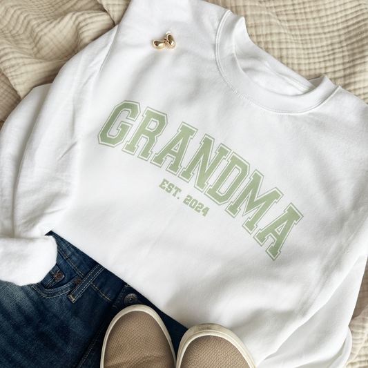 white pullover sweatshirt with a personalized grandma print in a varsity font featuring est. date 