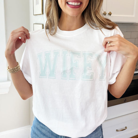 woman wearing a white t-shirt with custom wifey dusty blue dtf print across the chest