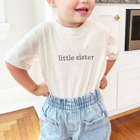 little girl wearing a natural heather tee with custom sibling personalization embroidered design