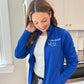 woman wearing a royal blue full zip polyester jacket with embroidered nurse stethoscope and custom name design on the left chest