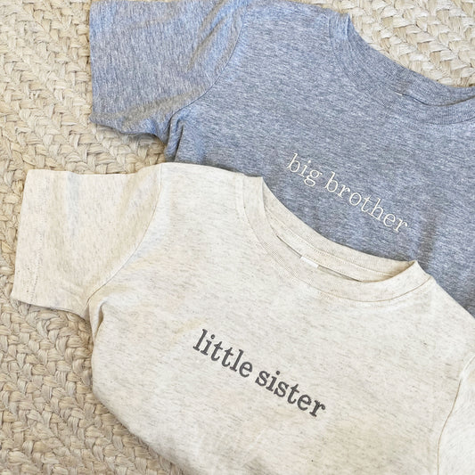 a heather grey tee and natural heather tee with custom sibling personalization embroidered design