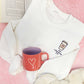 white crewneck sweatshirt with a to-go coffee cup design embroidered on the left chest