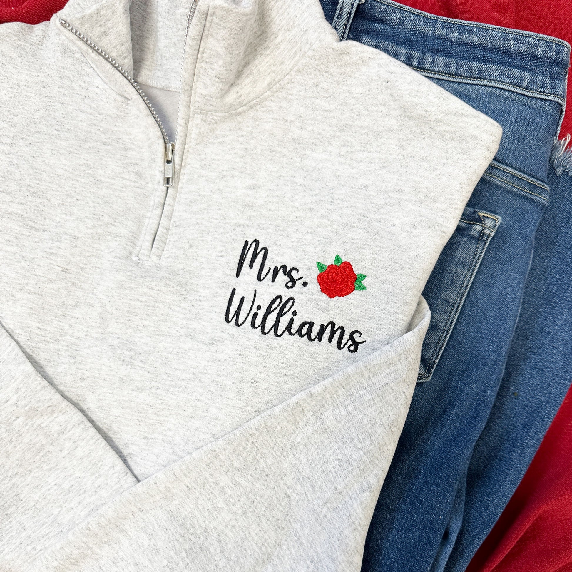 ash gray quarter zip with a custom name and mini rose embroidered design on the left chest