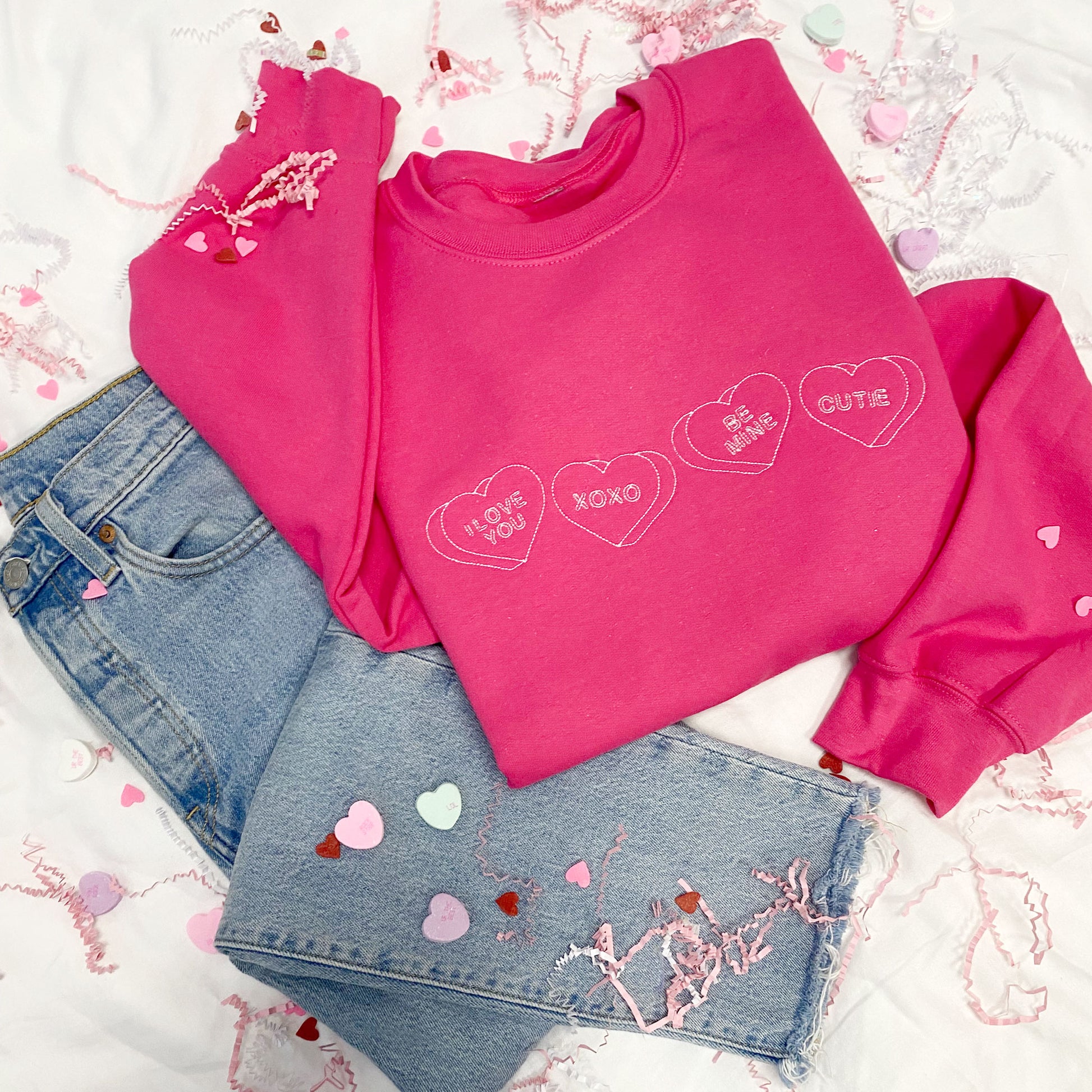 heliconia crewneck sweatshirt with candy heart embroidery designs saying "I love you," "xoxo," "be mine," and "cutie" across the chest.