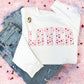 cute and colorful valentine's sweatshirt with LOVER printed in an athletic block font across the chest with a watercolor heart pattern fill.