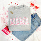gray sweatshirt with a valentine's inspired mama print across the chest featuring mini watercolor hearts paired with blue jeans and heart shaped sungalsses