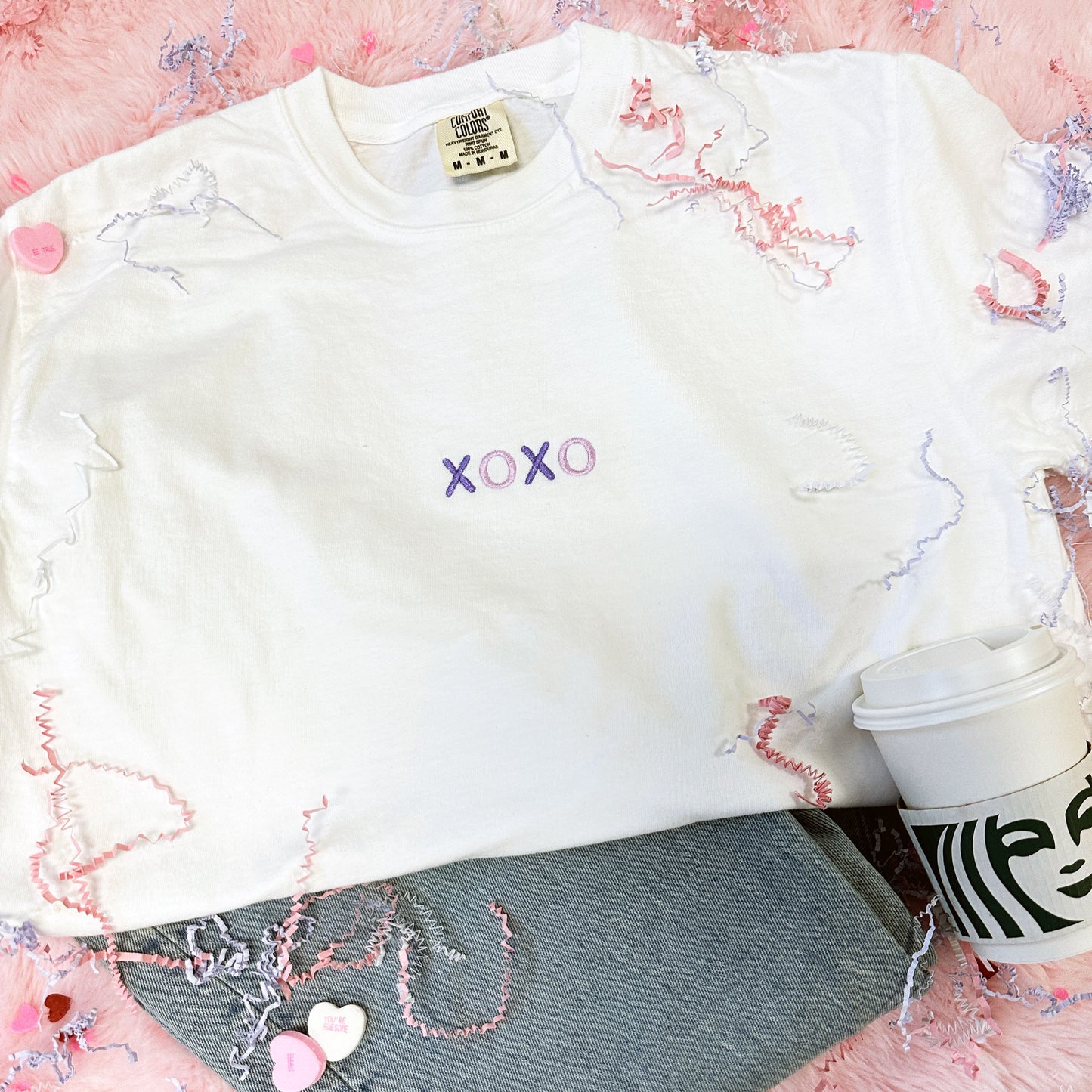styled white t-shirt with jeans and a starbucks coffee cup. Th e tshirt has xoxo embroidered small on the center chest in alternating purple  and lilac threads