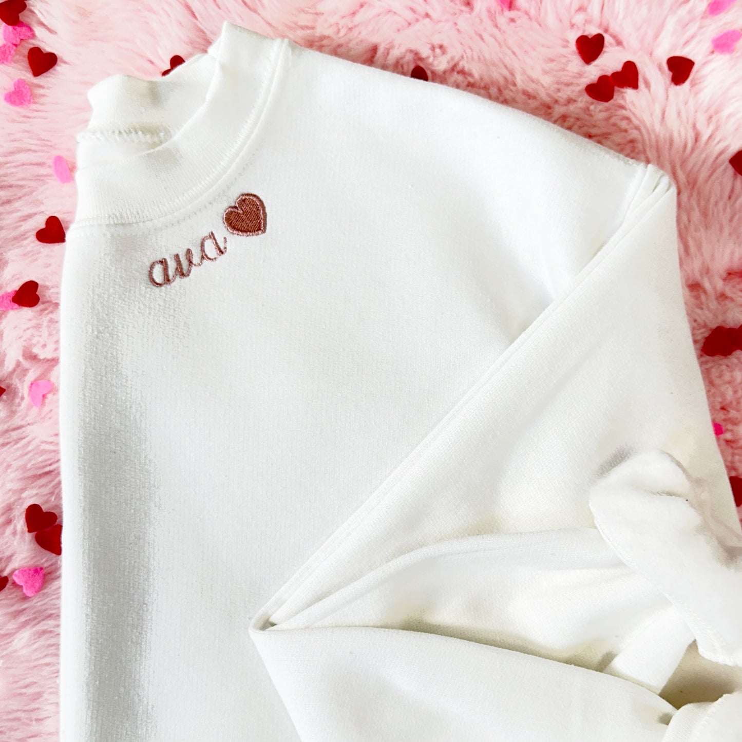 youth crewneck sweatshirt in white with a custom name neckline embroidery with mini heart