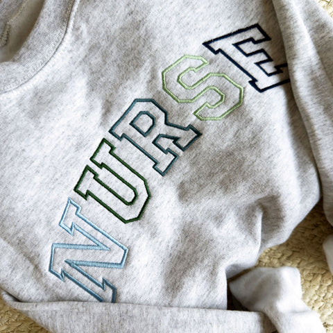 close up image of an embroidered nurse crewneck sweatshirt 