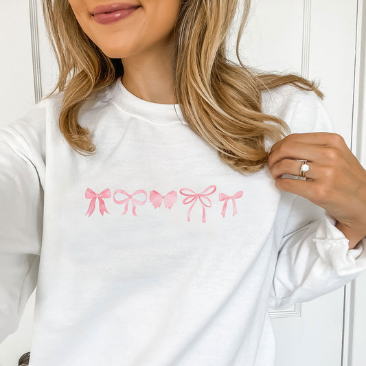 woman wearing a white crewneck sweatshirt with a mini pink bow printed design