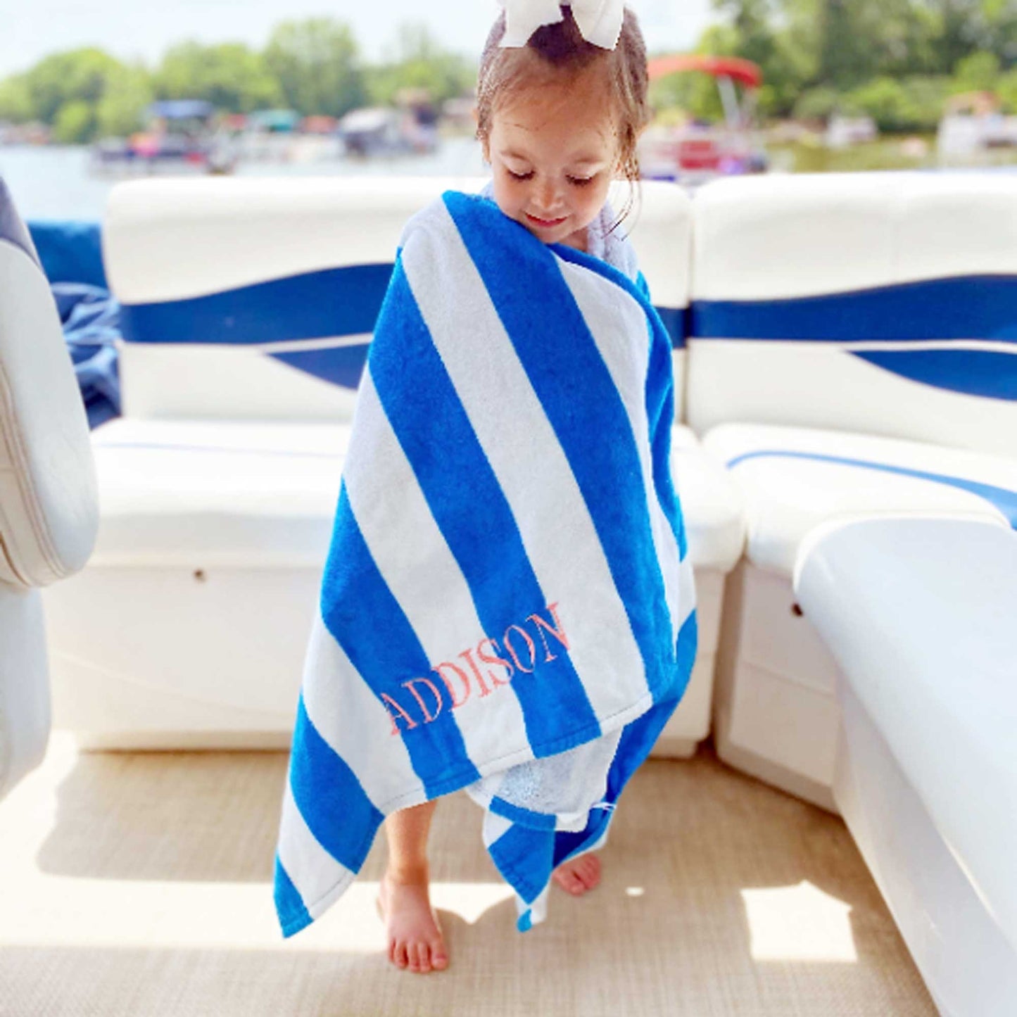 Little girl on a boat wrapped in a personalized striped beach towel