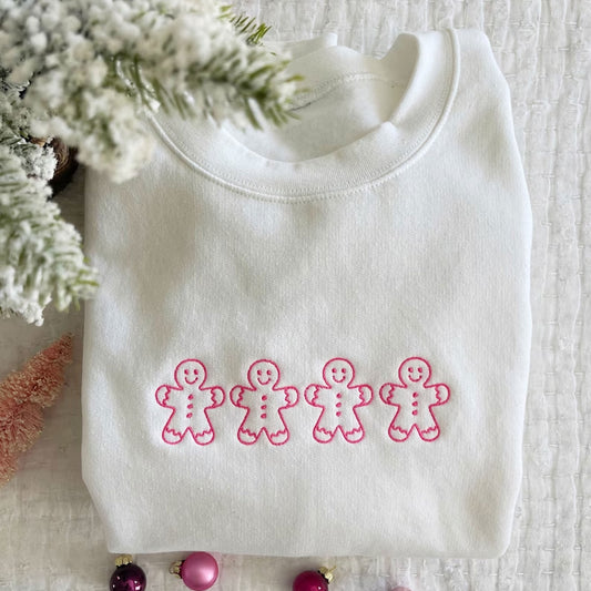 Flat lay image of a whie crewneck sweatshirt featuring 4 embroidered gingerbread men across the chest.