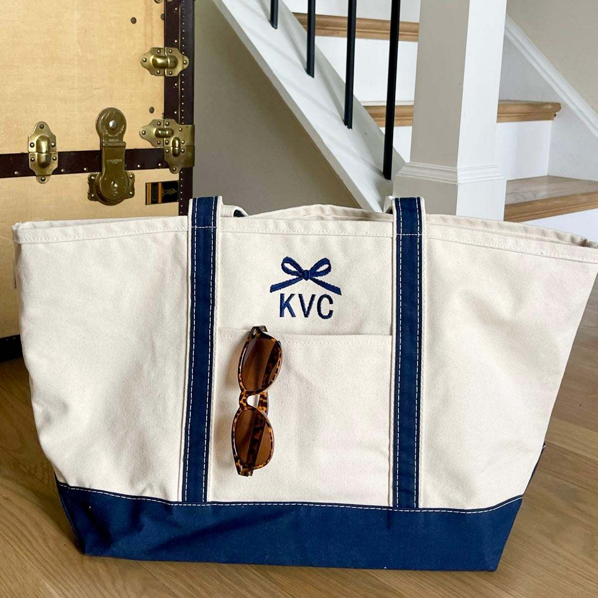 a natural canvas tote bag with navy trim and custom bow and initial embroidered design