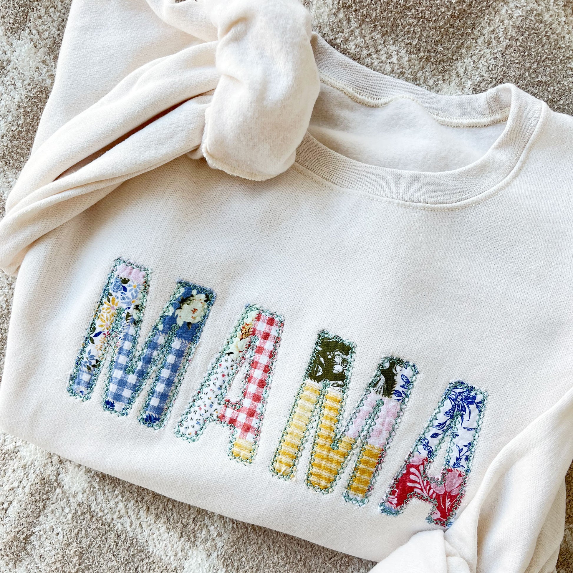 sweet cream crewneck sweatshirt with custom mama embroidered design featuring a vintage inspired patchwork quilted pattern with a raw edge for a homemade touch