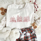 christmas styled flat lay of a sweet cream crewneck sweatshirt with embroidered stitched christmas village in red thread