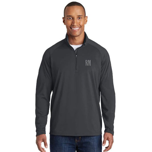 man wearing a charcoal gray athletic quarter zip featuring a two-letter custom embroidered monogram in a light gray thread on the left chest