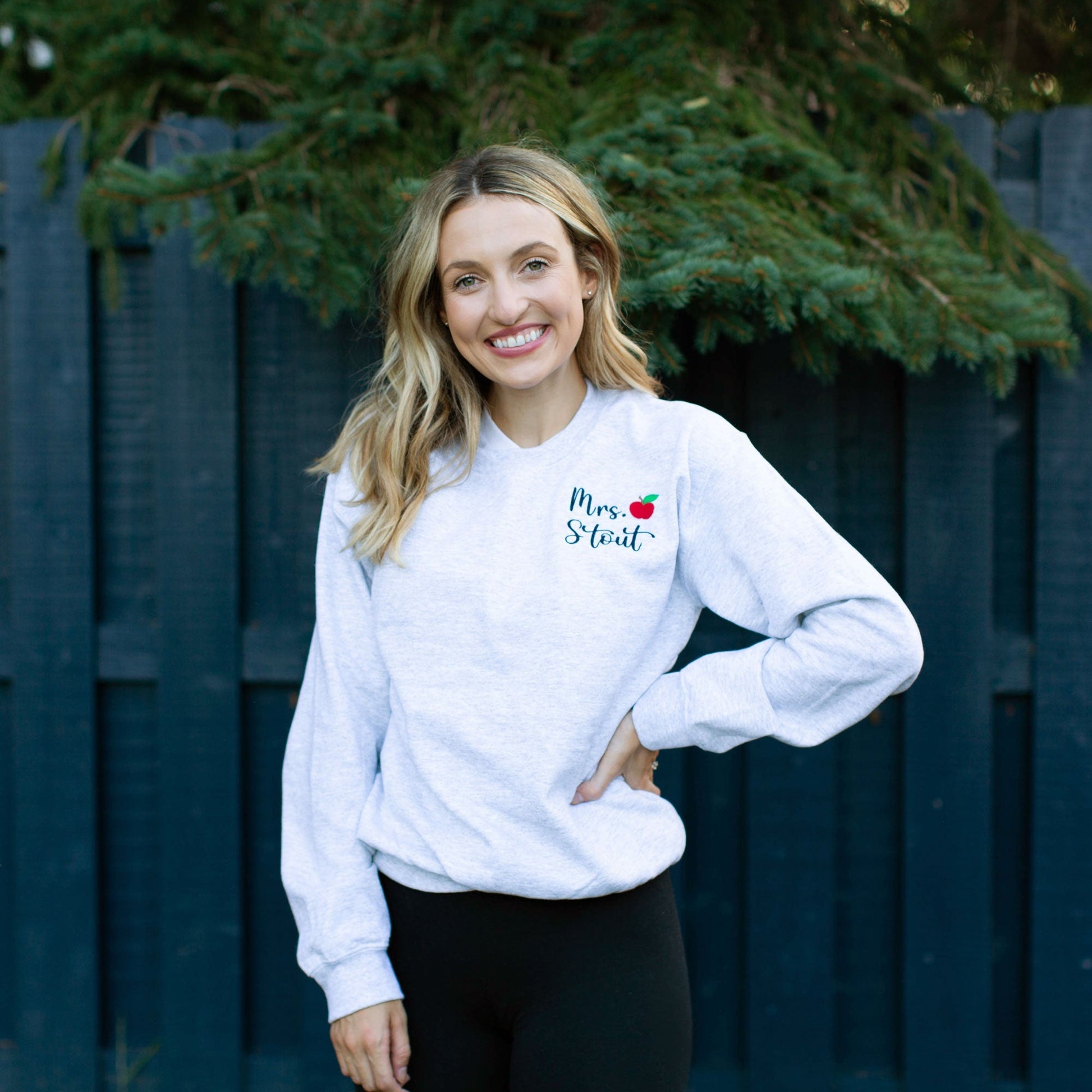 girl wearing a ash sweatshirt with custom name and mini apple embroidery